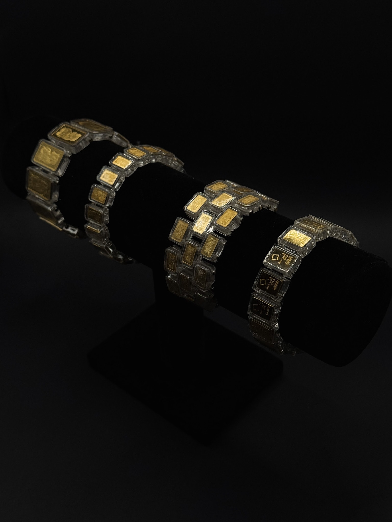 Transparent bracelet laid beside a grid of gold bars on marble